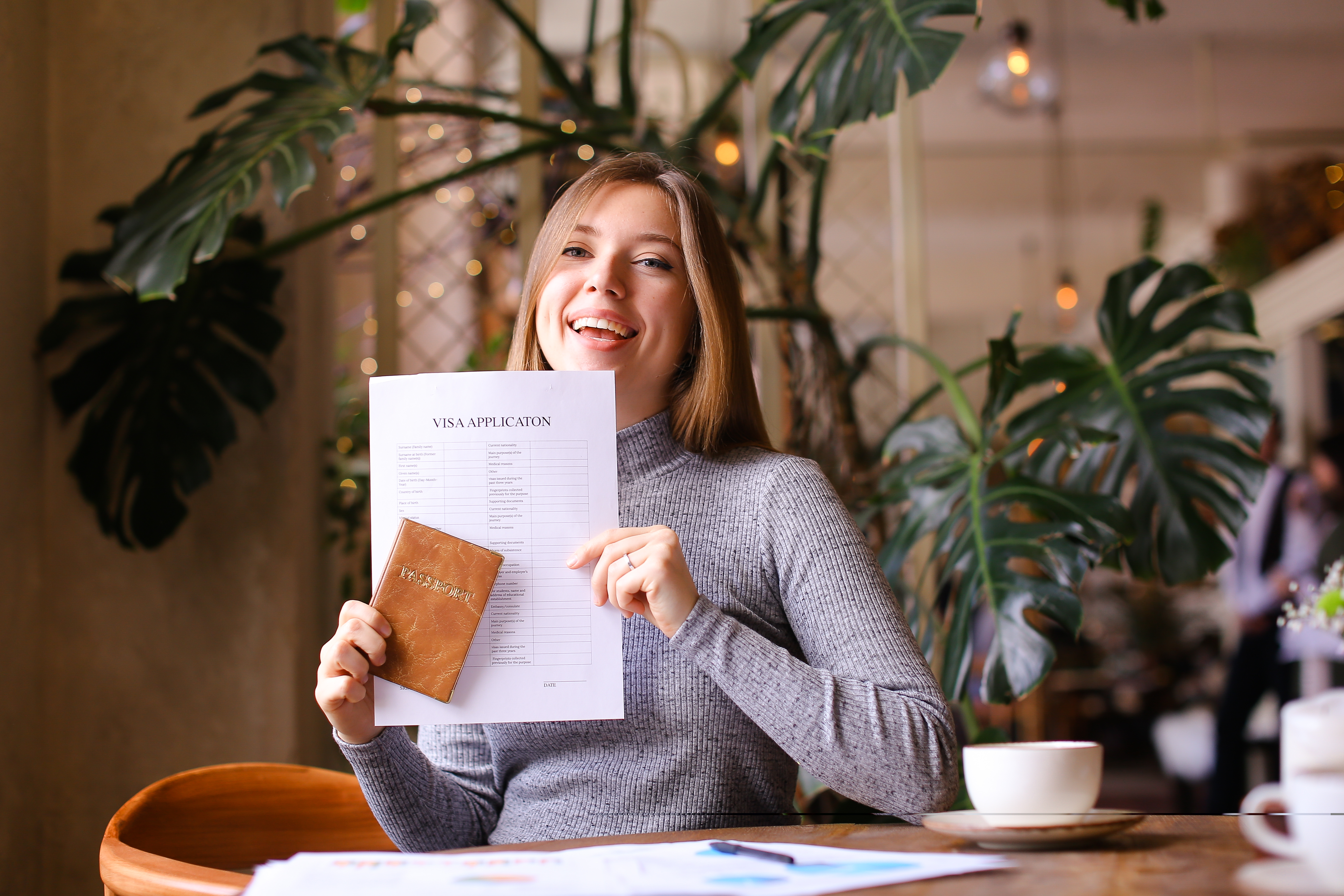 Pretty girl holding passport and visa application at travel agency cabinet