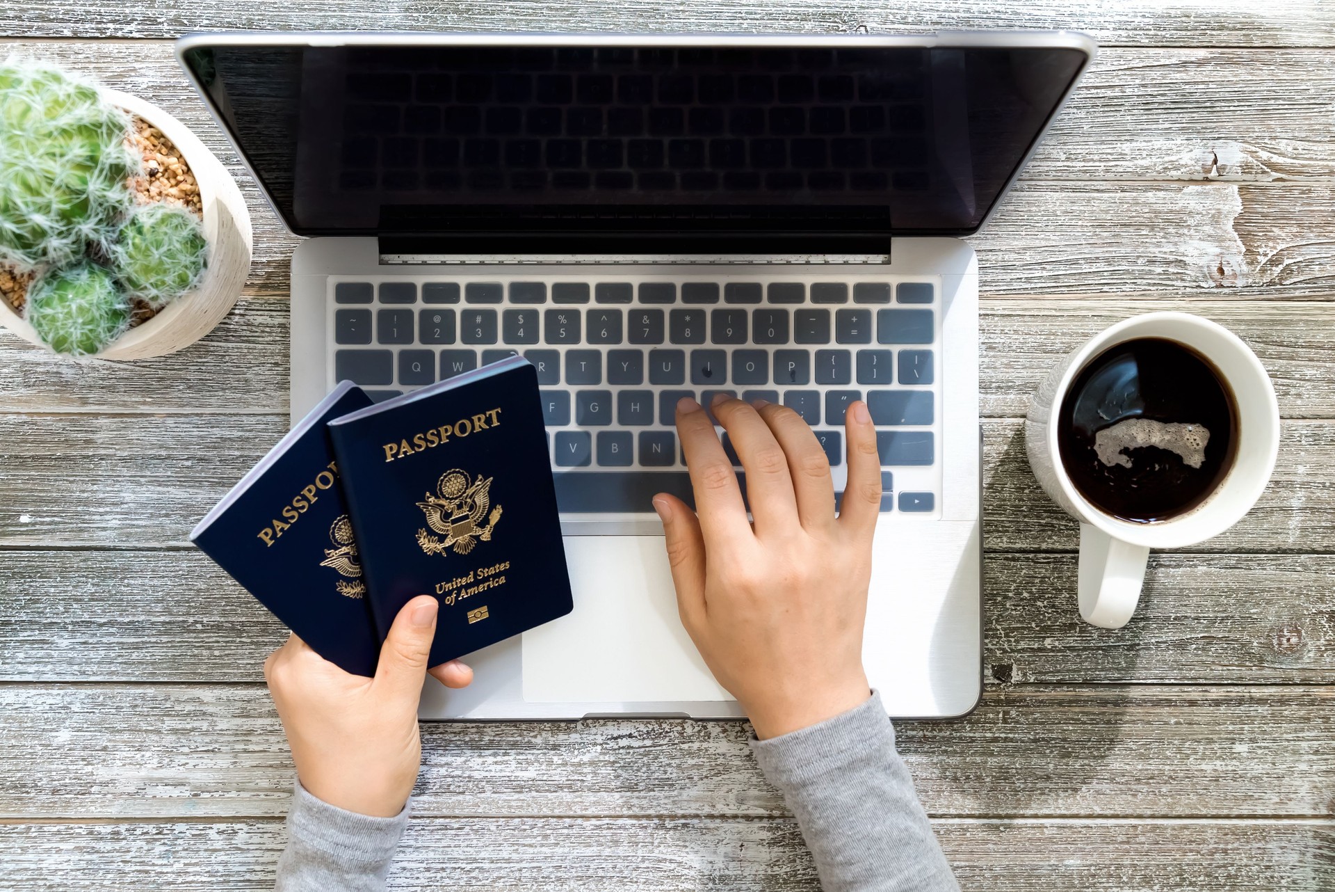 Person holding an American Passports while using a laptop